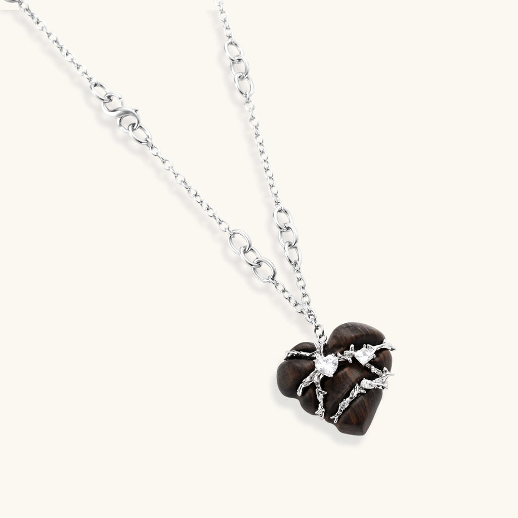 Dark ebony wood heart charms wrapped in intricate silver chains with crystal accents, shown as matching earrings and necklace set.