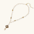 Y-shaped necklace with freshwater pearls, gold filigree stations, and ornate diamond-shaped centerpiece with pearl drop